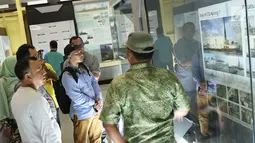 Pengunjung membaca informasi saat berkeliling Monumen Kapal Pembangkit Listrik Tenaga Diesel (PLTD) Apung 1 di Aceh, Selasa (31/7). Kapal berbobot mati 2.600 ton tersebut memiliki panjang 63 meter. (Liputan6.com/Immanuel Antonius)