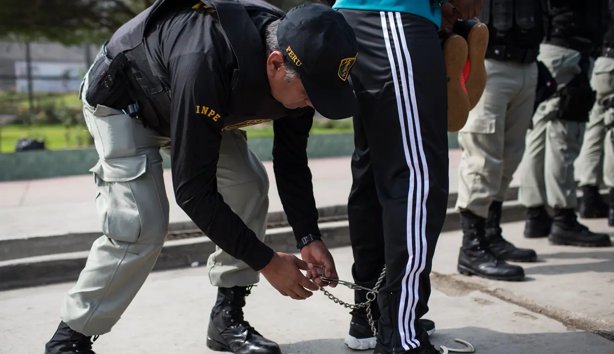 Penjaga membuka belenggu dari anggota tim sepak bola narapidana sebelum bermain di Penjara San Juan de Lurigancho, Lima, Peru, Kamis (24/5). (AP Photo/Rodrigo Abd)