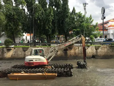 Pekerja menggunakan alat berat untuk mengeruk lumpur dan sampah yang mengendap di anak Sungai Ciliwung, Jakarta, Jumat (26/1). Pengerukan dilakukan untuk mencegah pendangkalan sungai. (Liputan6.com/Immanuel Antonius)