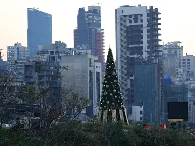 Sebuah pohon Natal dengan daftar nama korban yang tewas dalam insiden ledakan di Pelabuhan Beirut terlihat di dekat silo gandum yang rusak di Beirut, Lebanon (22/12/2020). Dua ledakan besar mengguncang Pelabuhan Beirut pada 4 Agustus lalu. (Xinhua/Bilal Jawich)