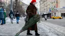 Seorang wanita membawa pohon untuk perayaan Tahun Baru dari sebuah pasar di pusat kota Moskow, Rusia (27/12/2020). (Xinhua/Maxim Chernavsky)