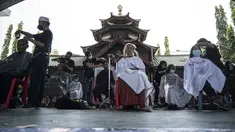 Penata rambut memberikan potongan rambut gratis sebagai bagian dari amal Muslim untuk yang membutuhkan saat umat Islam di seluruh dunia merayakan bulan suci Ramadhan di Muhammad Cheng Hoo di Surabaya (18/4/2022). (AFP/Juni Kriswanto)