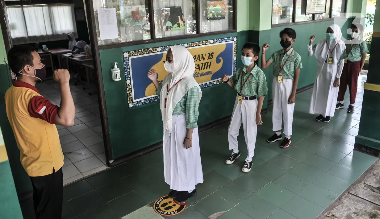 Guru mengatur barisan siswa sesuai jarak yang ditentukan sebelum memasuki ruang kelas di SDN Pekayon Jaya VI, Bekasi, Rabu (24/3/2021). Sekolah yang diberi izin menggelar pembelajaran tatap muka adalah yang berlokasi di zona hijau dan kuning. (merdeka.com/Iqbal S. Nugroho)