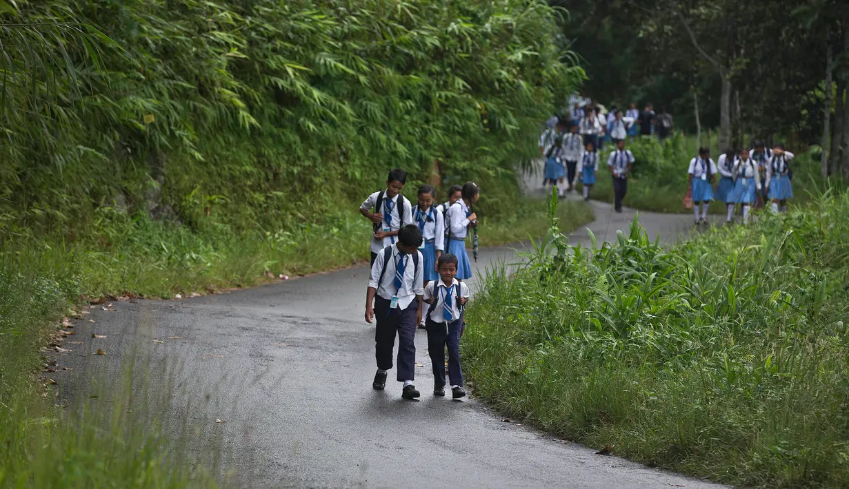 Para siswa suku Khasi kembali ke rumah dari sekolah saat hujan di sepanjang perbatasan negara Assam-Meghalaya di India (11/9). Musim hujan sangat penting di negara di mana 60 persen dari populasi bekerja di pertanian tersebut. (AP Photo/Anupam Nath)
