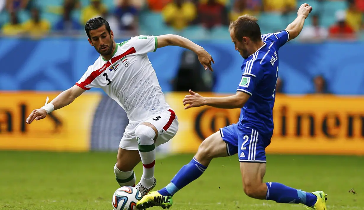 Pemain belakang Bosnia, Avdija Vrsajevic (kanan) berusaha merebut bola dari Ehsan Hajsafi (Iran) saat berlaga di penyisihan terakhir Piala Dunia 2014 Grup F di Stadion Fonte Nova, Salvador, Brasil, (25/6/2014). (REUTERS/Sergio Perez)