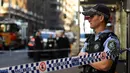 Seorang polisi berjaga di tempat kejadian setelah seorang pria menikam wanita dan berusaha menikam orang lain di pusat kota Sydney (13/8/2019). Pelaku penikaman berhasil ditangkap polisi setelah sejumlah warga melawan. (AFP Photo/Saeed Khan)