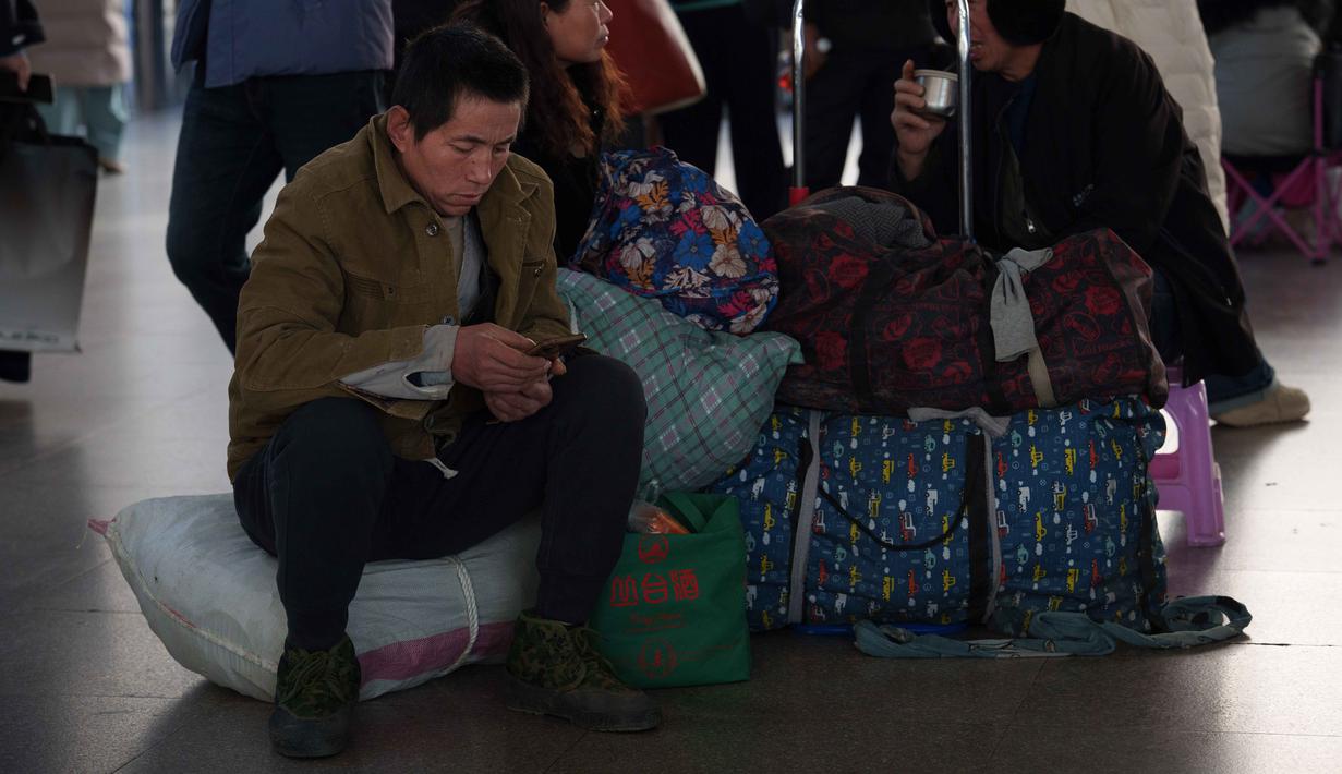 Angka tersebut akan menjadi rekor tertinggi sepanjang sejarah. Tampak dalam foto, seorang pria memeriksa ponselnya sambil duduk di samping tas-tas di stasiun kereta api saat orang-orang pulang kampung selama liburan Tahun Baru Imlek di Beijing, China, Selasa 10 Februari 2026. (AP Photo/Vincent Thian)
