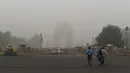 Turis menyebrang jalan untuk mengunjungi India Gate atau Gerbang India yang diselimuti kabut asap pekat di New Delhi, Minggu (3/10/2019). Ibu Kota dari India tersebut sedang dilanda polusi udara yang sangat buruk sekaligus beracun pekan ini. (Photo by Sajjad  HUSSAIN / AFP)