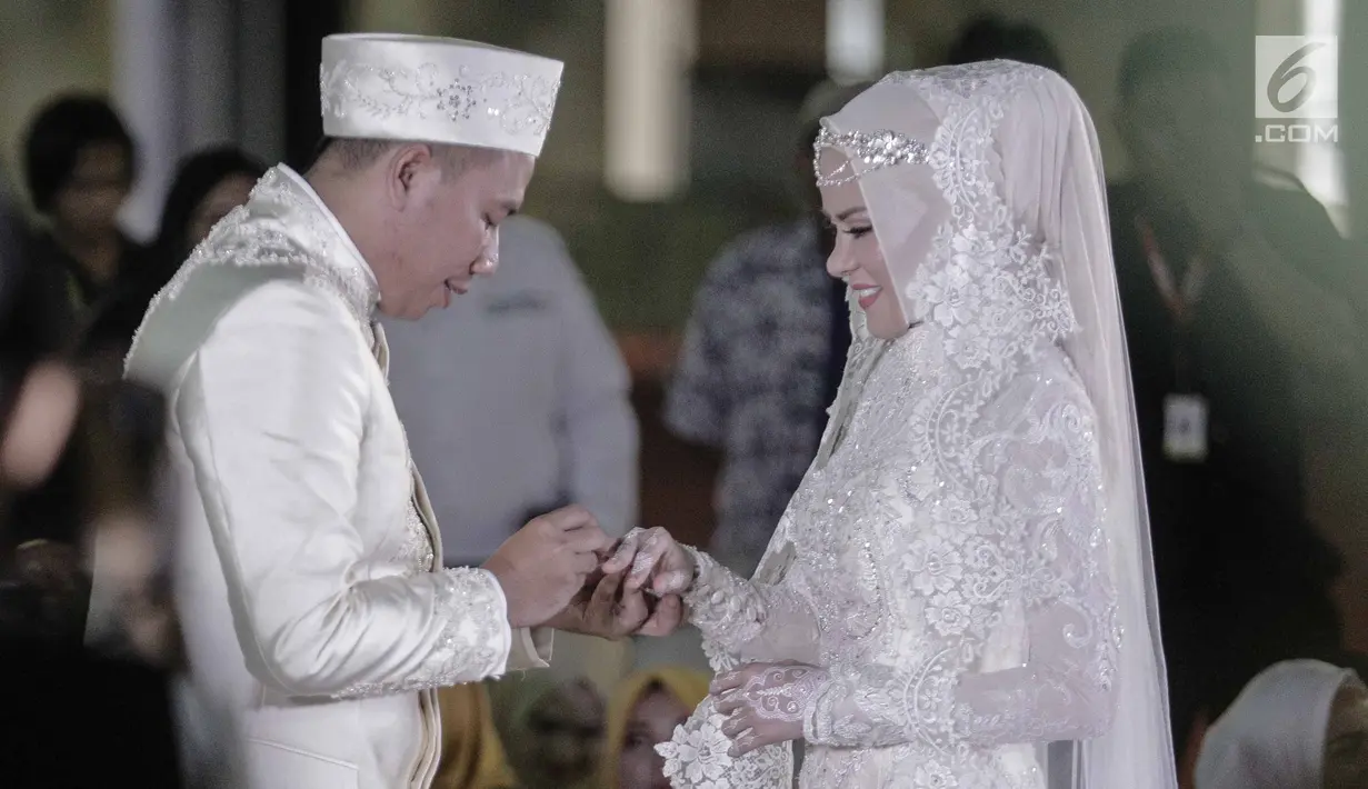 Vicky Prasetyo memasangkan cincin ke jari Angel Lelga saat akad nikah di Mesjid Istiqlal, Jakarta, Jumat (9/2). Surat Ar Rahman merupakan salah satu mahar pernikahan yang dipersembahkan Vicky untuk Angel Lelga. (Liputan6.com/Faizal Fanani)
