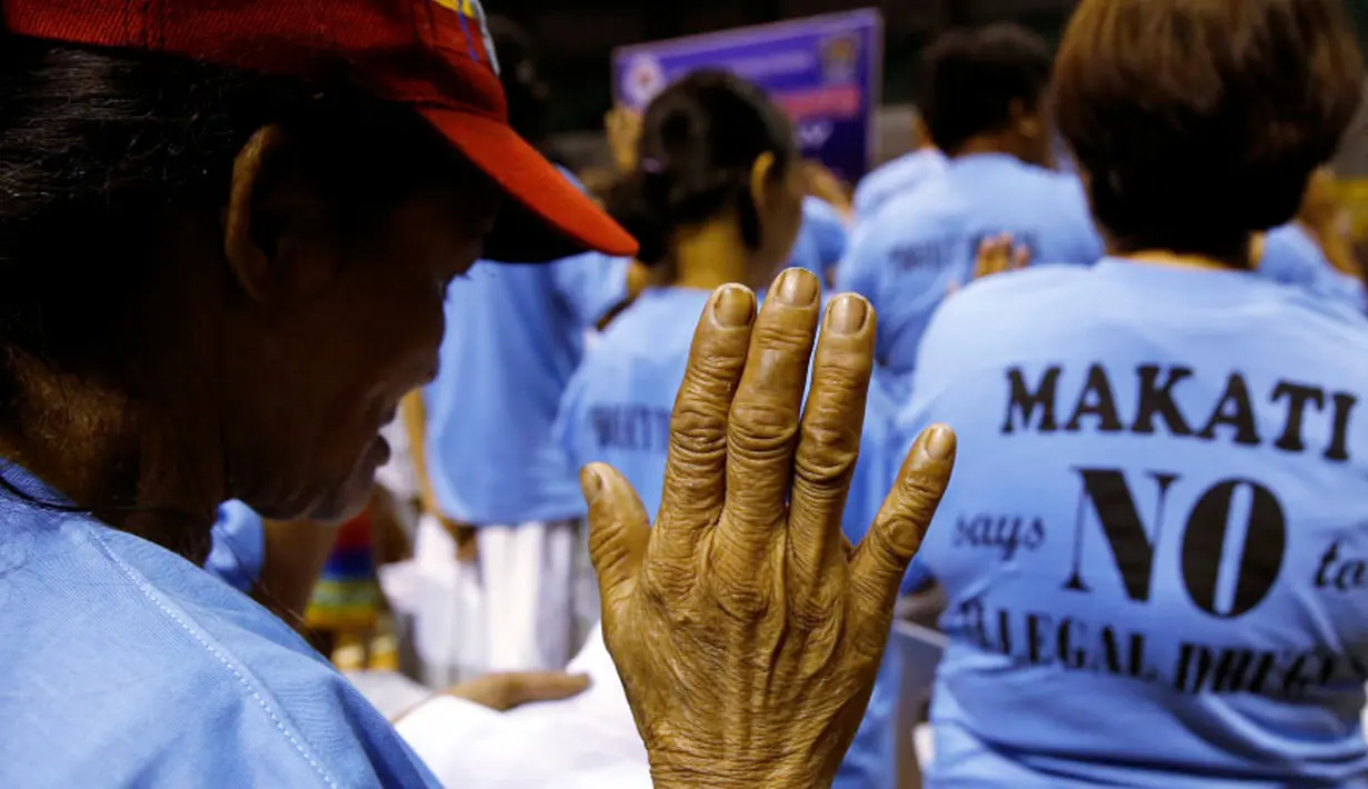 Pecandu narkoba mengambil sumpah saat bertobat di depan kepolisian di Makati, Manila, Filipina (18/8). Para pecandu narkoba menyerahkan diri lantaran marak teror penembakan misterius di Filipina. (Reuters/Eric Castro)