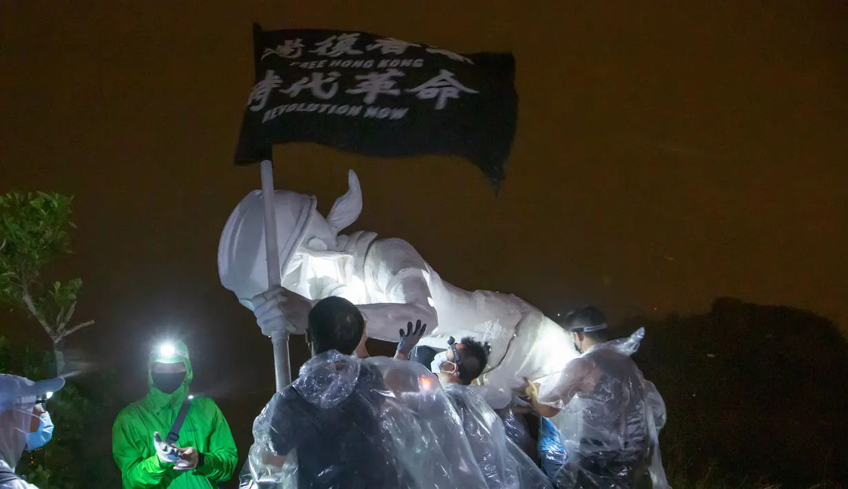 Demonstran antipemerintah mendirikan patung The Lady Liberty of Hong Kong di puncak pegunungan Lion Rock, Hong Kong, Minggu (13/10/2019). Patung tersebut memegang spanduk hitam yang bertuliskan 'Revolusi Zaman Kita, Bebaskan Hong Kong'. (AP Photo/Kin Cheung)