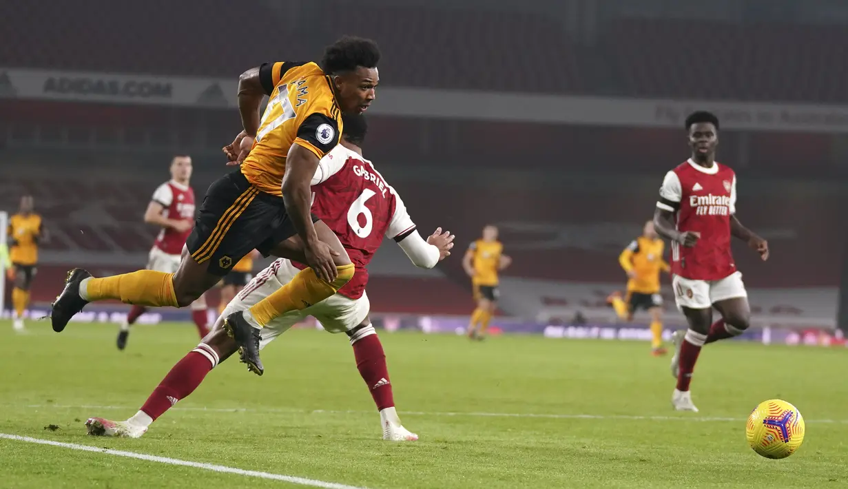 Penyerang Wolverhampton Wanderers, Adama Traore berebut bola dengan bek Arsenal, Gabriel pada pekan kesepuluh Liga Inggris di Emirates Stadium, London, Minggu (29/11/2020). Arsenal takluk 1-2 dari Wolverhampton Wanderers. (John Walton/Pool via AP)