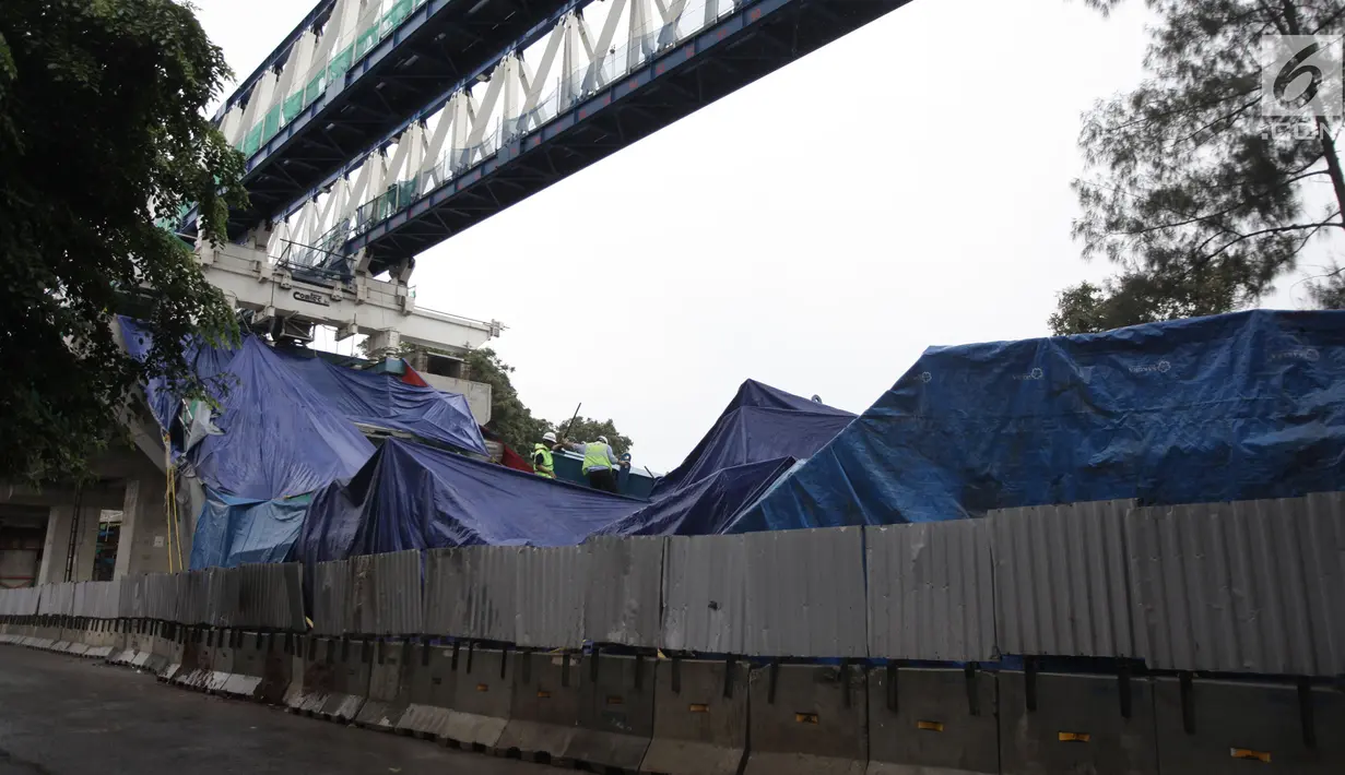 Petugas memeriksa kondisi box girder beton proyek light rapid transit ( LRT)  yang roboh di Kayu Putih, Jakarta Timur, Senin (22/1). Jalur yang roboh di tiang P28-P29 sudah ditutupi dengan terpal biru. (Liputan6.com/Arya Manggala)
