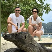 Berfoto bersama Komodo, Dian tampil dengan kaos bermotif garis-garis dipadu celana pendek dan sneakers. Lalu Anjasmara mengenakan kaos dan celana pendek putih. Credit: Instagram @bu_deedee