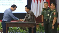 Direktur Utama BSI Hery Gunardi (kanan) dan Gubernur Lemhannas RI Andi Widjajanto (kiri) berjabat tangan usai menandatangani nota kesepahaman tentang pemanfaat produk dan layanan perbankan syariah di Gedung Pancagatra, Lemhannas, Jakarta (20/3/2023). (Liputan6.com/HO)