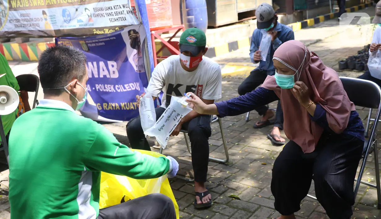 Warga memberikan kantong tes deteksi COVID-19 dengan metode GeNose C19 usai terjaring razia penggunaan masker di Kelurahan Sudimara Barat, Kota Tangerang, Kamis (27/5/2021). Tes tersebut untuk menekan penyebaran corona di wilayah tersebut. (Liputan6.com/Angga Yuniar)