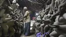 Perajin membuat patung Dewa Ganesha di sebuah bengkel di pinggiran Hyderabad, India, Rabu (18/8/2021). ​Patung ramah lingkungan yang dibuat jelang perayaan Ganesh Chaturthi tersebut dibuat dari lumpur, serat rami, dan bambu untuk mengurangi polusi air. (NOAH SEELAM/AFP)