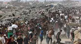 Orang-orang membawa bantuan berjalan di sepanjang jalan al-Rashid di Jabalia barat pada 22 Juni 2025, setelah truk bantuan kemanusiaan memasuki Jalur Gaza utara melalui perbatasan Zikim yang dikuasai Israel, di tengah perang yang sedang berlangsung antara Israel dan Hamas. (Omar AL-QATTAA/AFP)