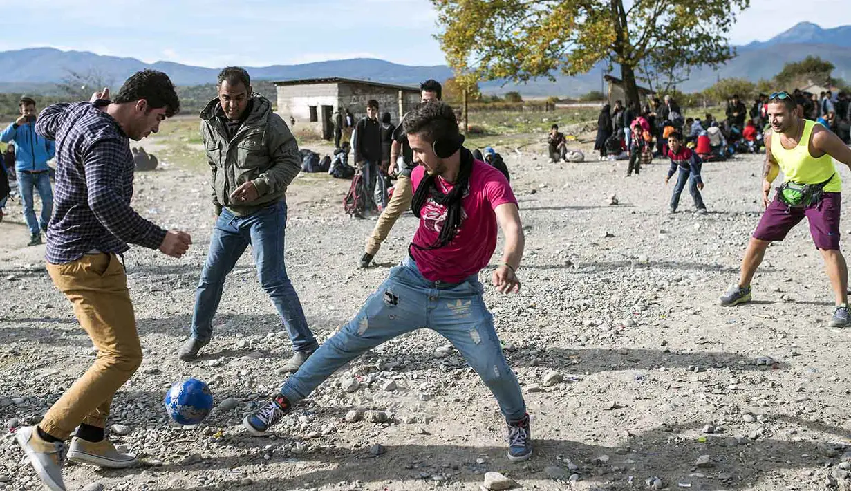 Imigran dan Pengungsi bermain bola sambil menunggu registrasi, sebelum melewati perbatasan Makedonia, Rabu (11/11/2015). AFP Photo/Robert Atanasovski).