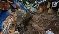 Alat berat mengeruk beton turap saluran air yang longsor di kawasan Jagakarsa, Jakarta, Kamis (17/9/2020). Selain karena hujan lebat, longsor diduga karena erosi tanah akibat pembuangan saluran air pencuci piring dan toilet dari warung makan di sekitar bantaran. (Liputan6.com/Immanuel Antonius)