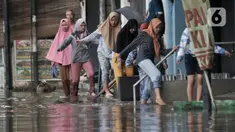 Warga melintasi banjir yang merendam Jalan RA Kartini, Bekasi, Jawa Barat, Kamis (2/1/2020). Banjir yang merendam Jalan RA Kartini sejak kemarin melumpuhkan akses kendaraan dan perekonomian warga setempat. (merdeka.com/Iqbal Nugroho)