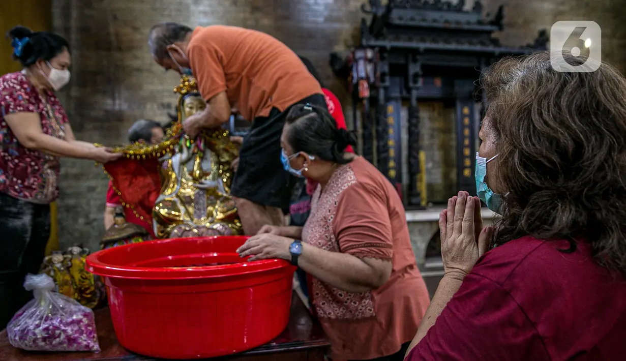 Seorang jemaat memperhatikan para jemaat lain yang sedang membersihkan patung di Vihara Amurva Bhumi, Jakarta, Kamis (4/2/2021). Ritual mencuci patung dewa serta bersih-bersih ini dilakukan dalam rangka menyambut perayaan Tahun Baru Imlek 2572. (Liputan6.com/Faizal Fanani)