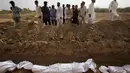 Sejumlah warga melihat proses pemakaman massal korban tewas akibat gelombang panas di Karachi, Pakistan, Jumat (26/6/2015). Lebih dari 1.150 orang tewas akibat gelombang panas. (REUTERS/Akhtar Soomro)