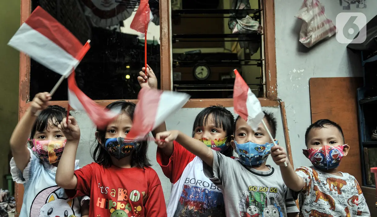 Anak-anak membawa bendera Merah Putih di Gang A, RT 10/11, Pademangan Timur, Jakarta, Rabu (5/8/2020). Dalam rangka menyambut HUT ke-75 RI, gang tersebut bersolek dengan mewarnai jalan hingga memasang bendera Merah Putih serta beragam atribut kemerdekaan. (merdeka.com/Iqbal S. Nugroho)