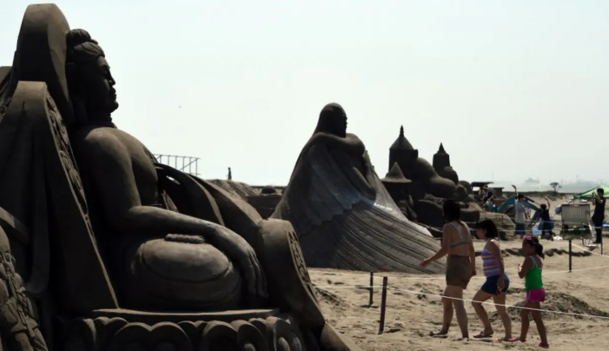 Pengunjung berjalan diantara patung pasir di pameran Asahi Sand Sculpture, Yasashigaura, pantai Asahi , Tokyo, Sabtu (11/7/2015). Pameran ini digelar mulai Senin (6/7) lalu. (AFP PHOTO/Toshifumi Kitamura)