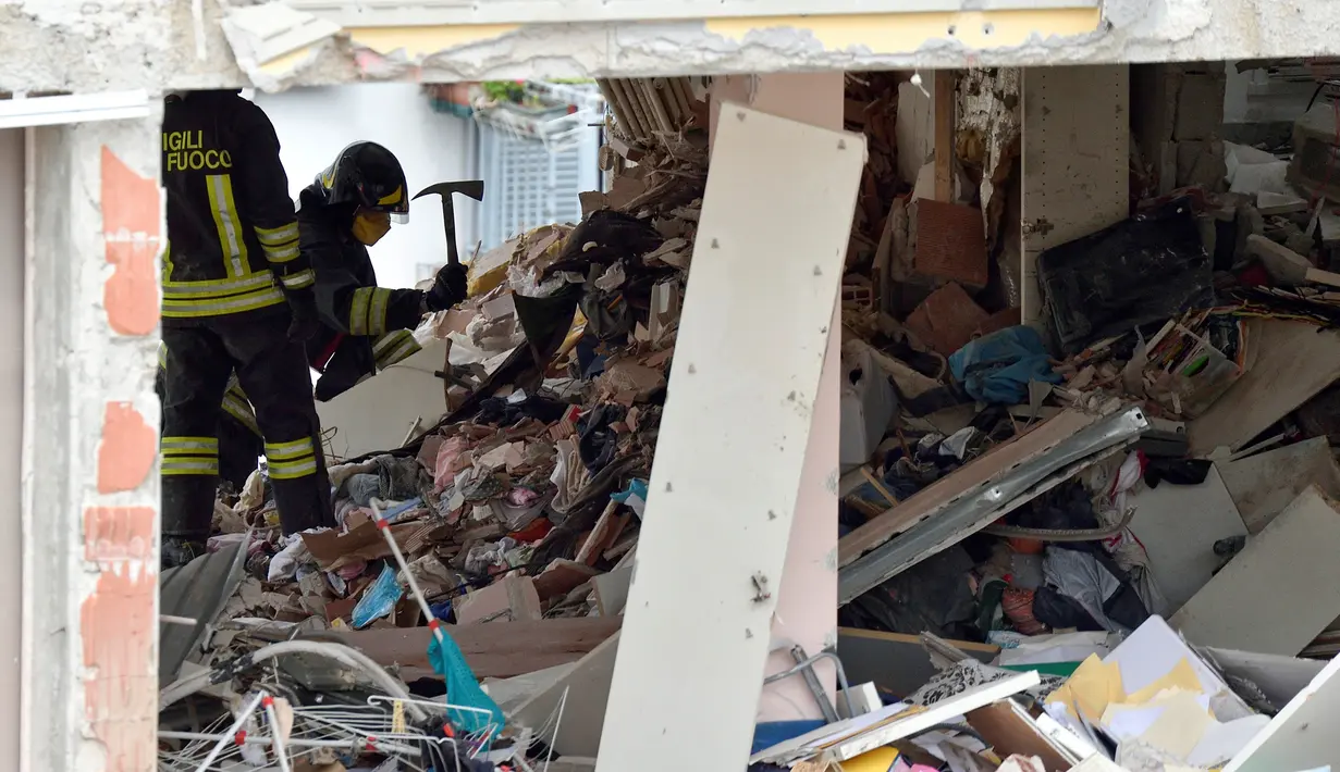 Pemadam kebakaran mencari korban di reruntuhan rumah susun yang roboh akibat ledakan di Milan, Italia, Minggu (12/6) waktu setempat. Sedikitnya tiga orang tewas akibat ledakan yang berasal dari lantai tiga bangunan tersebut. (REUTERS/Flavio Lo Scalzo)