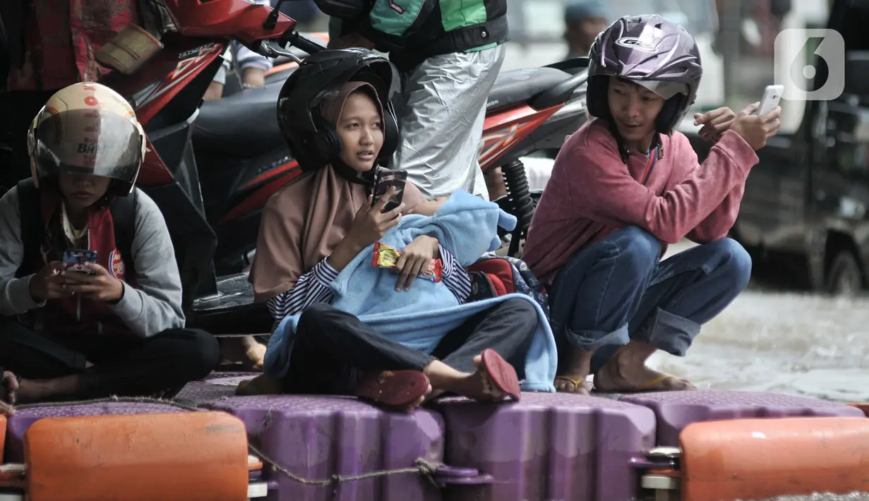 Pengendara sepeda motor menggunakan jasa rakit saat banjir melanda Cempaka Putih, Jakarta, Minggu (23/2/2020). Pengendara memanfaatkan jasa angkutan rakit yang ditawarkan warga agar dapat melewati banjir. (merdeka.com/Iqbal S. Nugroho)