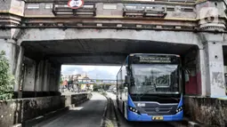 Bus Transjakarta melintas di bawah Jembatan Kereta Matraman, Jakarta Timur, Senin (10/1/2022). Penetapan Jembatan Kereta Matraman sebagai cagar budaya dilakukan untuk pelestarian sekaligus memperkenalkan masyarakat tentang sejarah di Ibu Kota. (merdeka.com/Iqbal S. Nugroho)