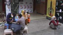 Perempuan yang mengenakan masker mendapatkan desain henna di tangan mereka pada malam festival Karva Chauth di New Delhi, India, Selasa (3/11/2020). Ini adalah festival untuk memulai bulan baru di bulan November di mana para istri akan berpuasa untuk suami-suami mereka. (AP Photo/Manish Swarup)