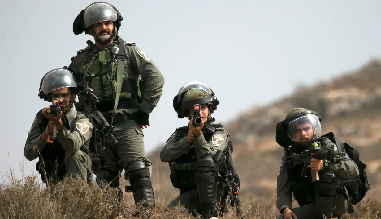Pasukan penjaga perbatasan Israel membidik saat bentrok dengan pengunjuk rasa Palestina di Ramallah, Tepi Barat, Kamis (17/10/2019). Pengunjuk rasa menentang pembangunan pos terdepan Israel di dekat desa Palestina, Turmus Ayya, dan pemukiman Israel, Shilo. (JAAFAR ASHTIYEH/AFP)