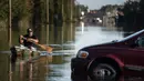 Eric Locklear mendayung kano melewati mobil yang terendam banjir di Lumberton, Carolina Utara, AS, 12 Oktober 2016. Banjir akibat badai Matthew tersebut merendam kota berpenduduk 21.000 orang itu. (Sean Rayford/Getty Images/AFP)