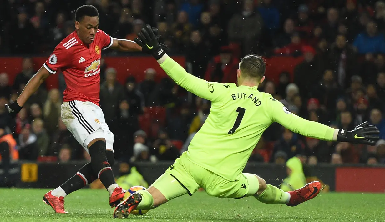 Kiper Stoke City, Jack Butland menghadang tendangan striker Manchester United, Anthony Martia pada laga pekan ke-23 Premier League 2017-2018 di Old Trafford, Senin (15/1). Satu gol Martia membawa Manchester United menang dengan skor 3-0. (Oli SCARFF/AFP)