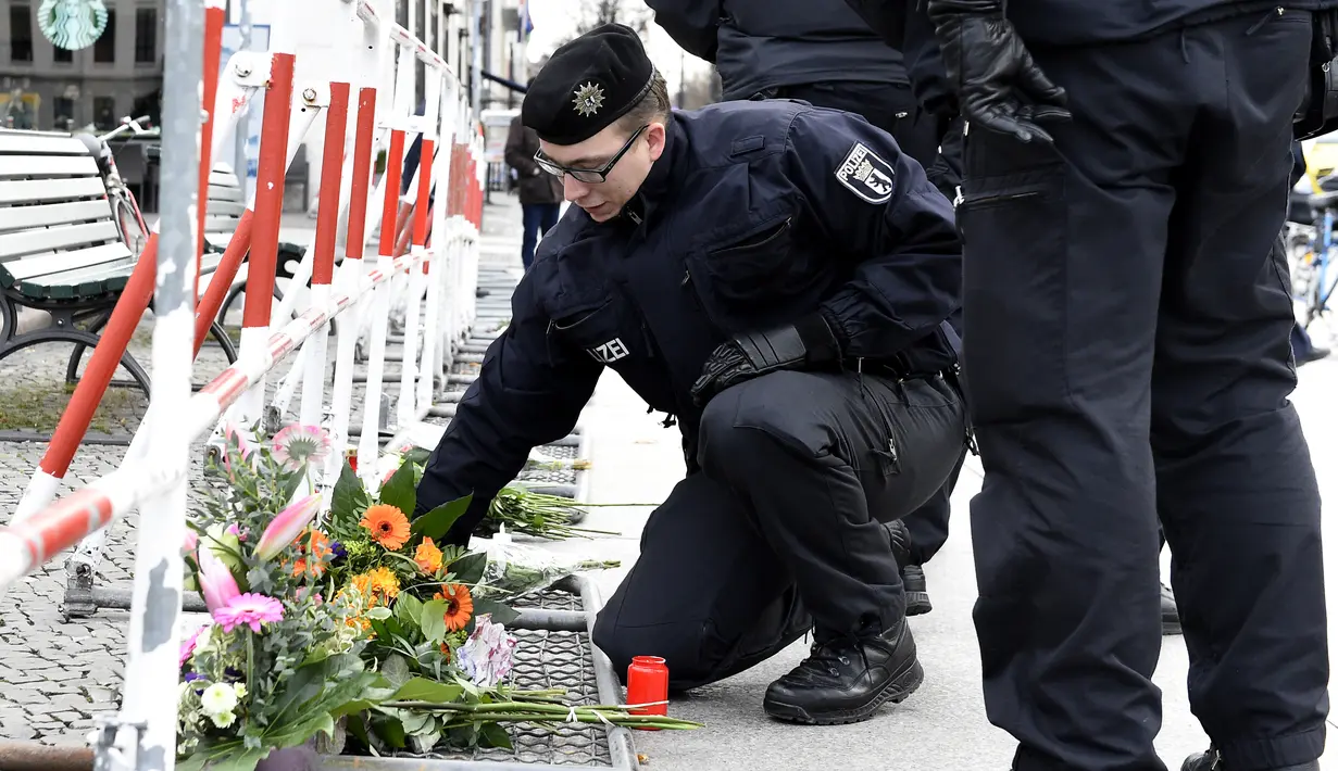Polisi Jerman mengatur bunga yang dibawa oleh orang-orang di depan Kedutaan Besar Prancis di Berlin, Sabtu (14/11/2015). Karangan bunga tersebut untuk menghormati para korban serangan mematikan di Paris. (AFP Photo/ Tobias Schwarz)
