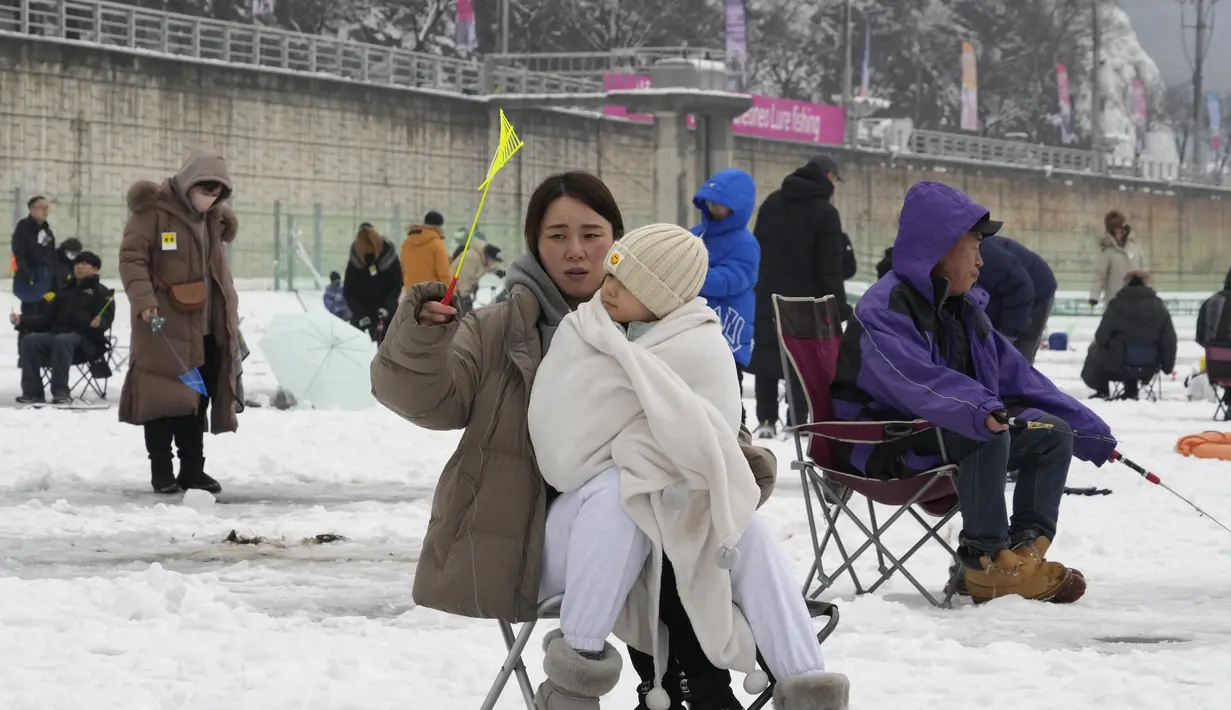 Seorang wanita melemparkan tali melalui lubang yang dibor di permukaan sungai beku selama kontes menangkap ikan trout di Hwacheon, Korea Selatan, Sabtu (7/1/2023). Kontes ini merupakan bagian dari festival es tahunan yang menarik lebih dari satu juta pengunjung setiap tahun. (AP Photo/Ahn Young-joon)