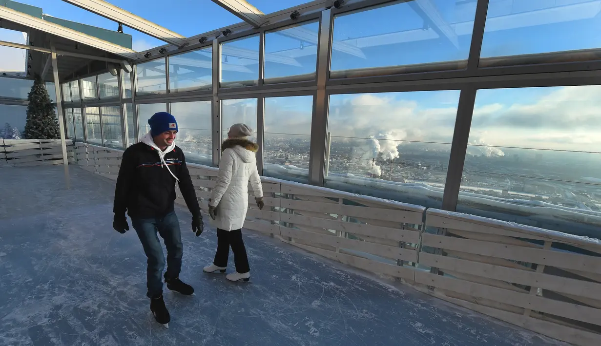 Dua wisatawan tengah menikmati keseruan bermain ice skating di arena ski lantai teratas pusat bisnis Oko Tower di Moskow, Rusia, Kamis (15/12). Arena ski yang berada di ketinggian 354 meter ini diklaim menjadi yang tertinggi di Eropa. (VASILY MAXIMOV/AFP)