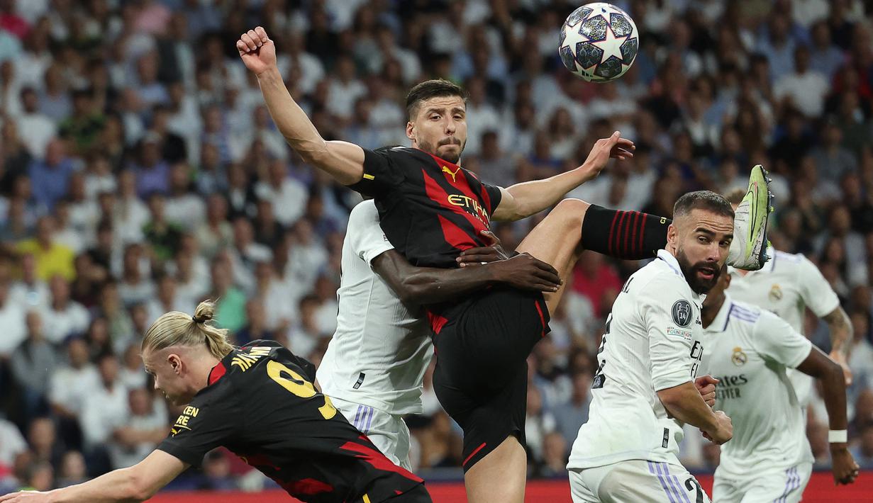 Bek Manchester City, Ruben Dias (tengah) berebut bola dengan bek Real Madrid, Dani Carvajal (kanan) pada laga leg pertama semifinal Liga Champions 2022/2023 di Santiago Bernabeu Stadium, Madrid (9/5/2023). Ruben Dias yang baru tiga musim membela Manchester City ini kini memiliki nilai pasar 75 juta euro atau setara Rp1,2 triliun. (AFP/Thomas Coex)