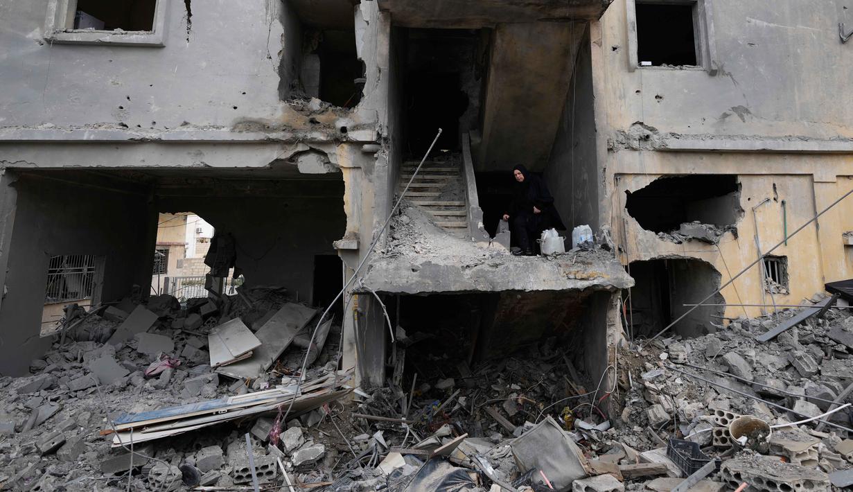 Serangan udara Israel menyasar sejumlah wilayah di Lebanon, terutama selatan dan pinggiran Kota Beirut. Tampak dalam foto, seorang wanita menaiki tangga di sebuah bangunan yang hancur akibat serangan udara Israel di kota pelabuhan Tyre, Lebanon selatan, Kamis, 26 Maret 2026. (AP Photo/Hussein Malla)