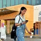 Manahel Otaibi, 25, memeriksa teleponnya saat dia berjalan dengan pakaian ala Barat di Tahlia Street, Riyadh, Arab Saudi, pada 2 September 2019. (Fayez Nureldine / AFP)