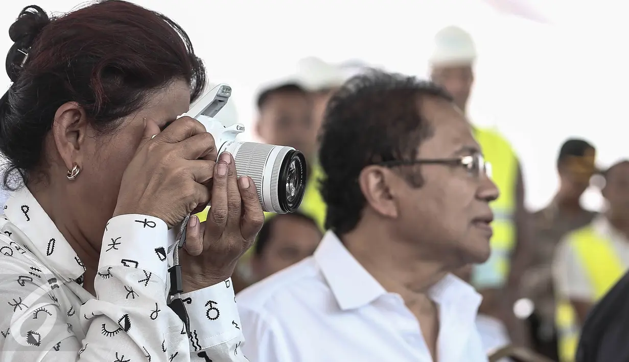 Menteri Kelautan dan Perikanan, Susi Pudjiastuti memotret dengan kamera kesayangan miliknya ketika meninjau reklamasi Teluk Jakarta, Rabu (4/5). Kegemaran memotret ditularkan sang ayah yang merupakan juru foto sewaktu muda. (Liputan6.com/Faizal Fanani)