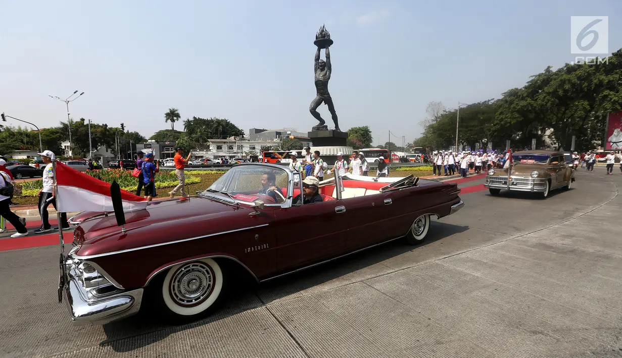 Mobil klasik memeriahkan prosesi Torch Relay Asian Games 2018 di Jalan Jendral Sudirman, Jakarta, Sabtu (18/8). Hari terakhir kirab obor ini api abadi dibawa dari Tugu Monas hingga Gelora Bung Karno. (Liputan6.com/ Fery Pradolo)