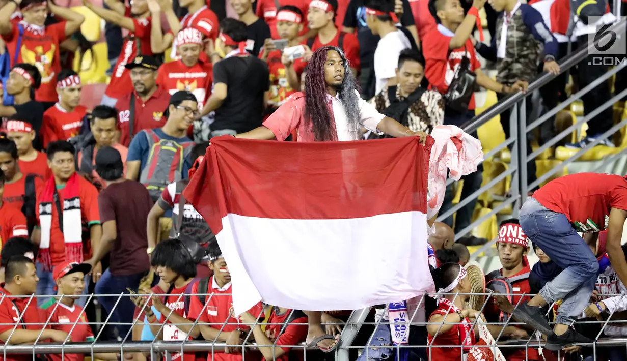 Suporter timnas Indonesia U-22 membentangkan bendera Merah Putih saat menyaksikan laga penyisihan Grup B melawan Vietnam di Stadion Selayang, Selangor, Selasa (22/8). Indonesia bermain imbang melawan Vietnam dengan skor 0-0. (Liputan6.com/Faizal Fanani)