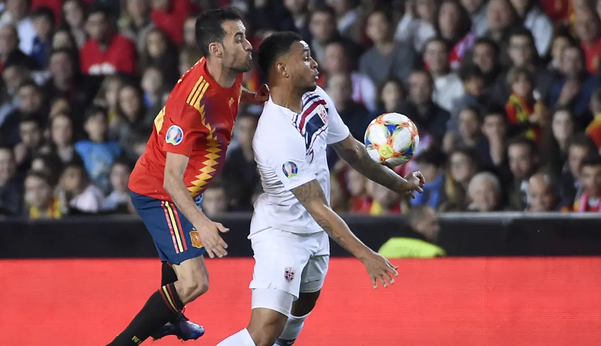 Gelandang Spanyol, Sergio Busquets, berusaha menjaga striker Norwegia, Joshua King, pada laga Kualifikasi Piala Eropa 2020 di Stadion Mestalla, Valencia, Sabtu (23/3). Spanyol menang 2-1 atas Norwegia. (AFP/Jose Jordan)