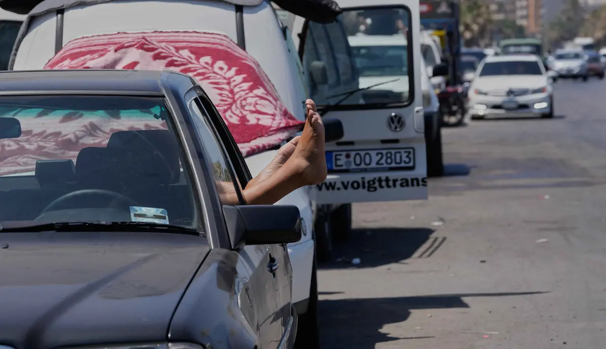 Seorang pengungsi yang meninggalkan desanya di Lebanon Selatan meregangkan kakinya dari mobil tempat ia berlindung di jalan kota pelabuhan selatan Sidon, Rabu 10 Juni 2026. (AP Photo/Mohammed Zaatari)
