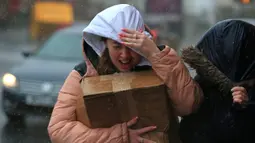 Seorang wanita berusaha melindungi dirinya dari angin kencang dan hujan di Sheffield, Inggris utara (9/2/2020). Badai Ciara diperkirakan akan mengganggu penerbangan, kereta api dan laut dan membatalkan acara olahraga, memutus tenaga listrik dan merusak properti. (AFP Photo/Lindsey Parnaby)