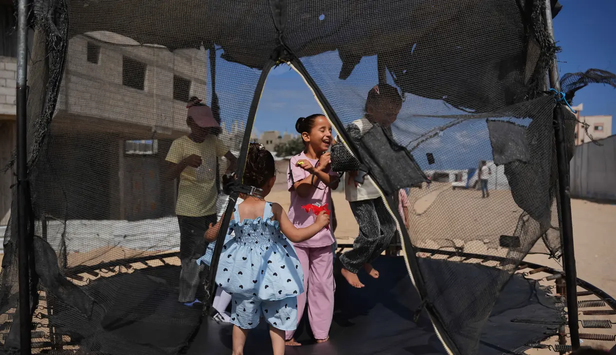 Anak-anak pengungsi Palestina bermain trampolin di sebuah kamp tenda selama Hari Raya Idul Adha di Khan Younis, Jalur Gaza, Rabu 27 Mei 2026. (AP Photo/Abdel Kareem Hana)