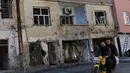  Warga melewati bangunan yang rusak akibat konflik antara Militer Turki dan Militan Kurdi di Turki, (7/12). Militan Kurdi dan afiliasinya Partai Pekerja Kurdi (PKK) dilabeli oleh pemerintah Ankara sebagai kelompok teroris. (REUTERS/Murad Sezer)